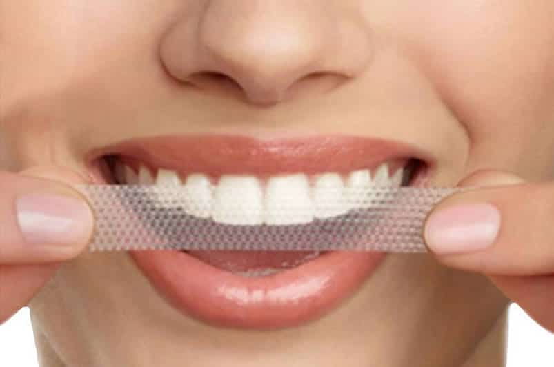 Woman using teeth whitening strip