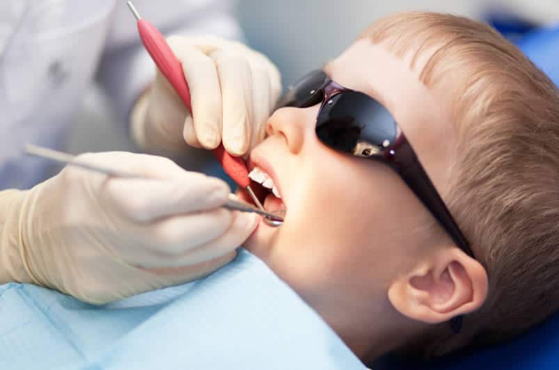 dental professional performing laser dentistry on pediatric patient wearing protective shades