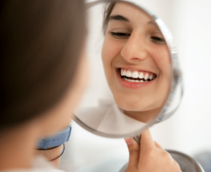 young woman with white teeth smiling looking in mirror