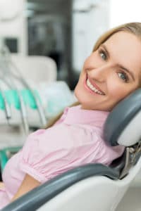 A happy caucasian woman looking back smiling in a dental chair after a teeth whitening procedure
