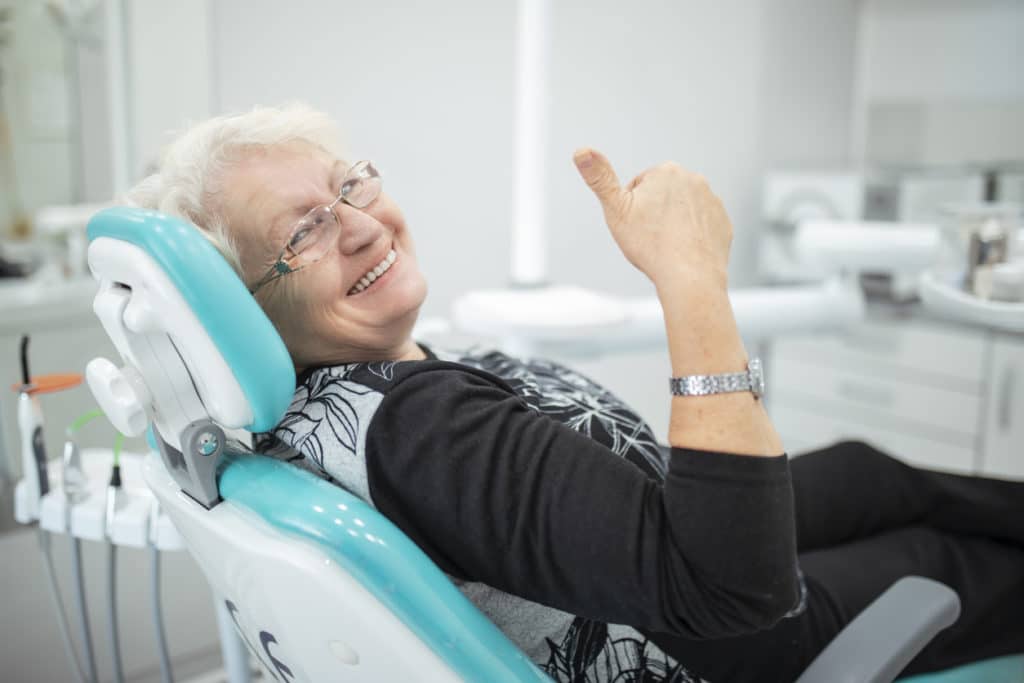 elderly woman smiling sitting in dentist chair