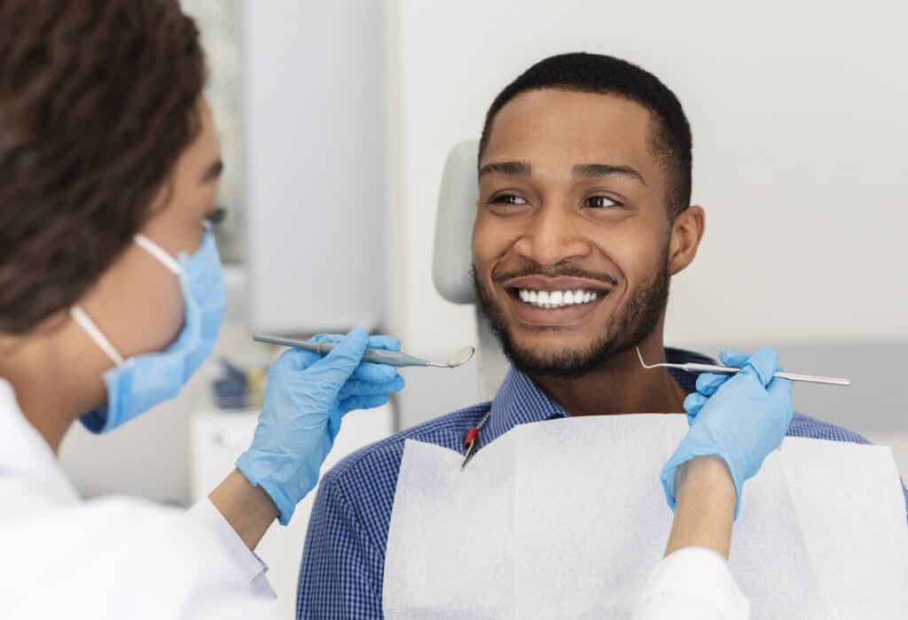 female dentist in mask and gloves consulting male patient