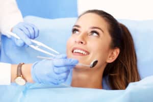 Pretty woman smiling in dentist chair as dentist examines her teeth after getting tooth-colored fillings
