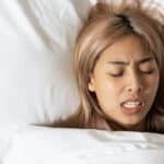 A woman with bruxism and sleep apnea lying in bed