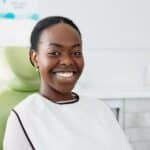 A woman smiling and sitting in a chair for a laser dentistry appointment