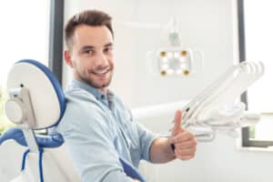 A man sitting in a dentist's chair and giving a thumb's up after laser dentistry in Pasadena