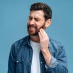 A man who needs to replace a dental filling holding his jaw